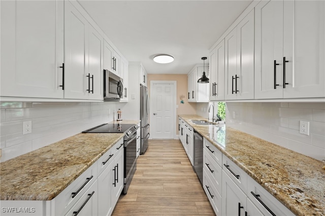 kitchen featuring pendant lighting, appliances with stainless steel finishes, light stone countertops, and white cabinets