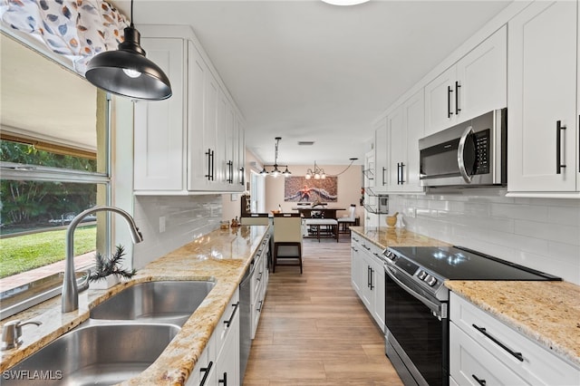 kitchen featuring decorative light fixtures, white cabinetry, sink, and stainless steel appliances