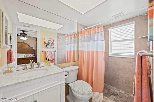 bathroom with toilet, ceiling fan, vanity, and walk in shower