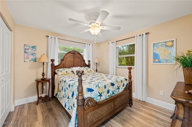 bedroom with light wood-type flooring, ceiling fan, and a closet