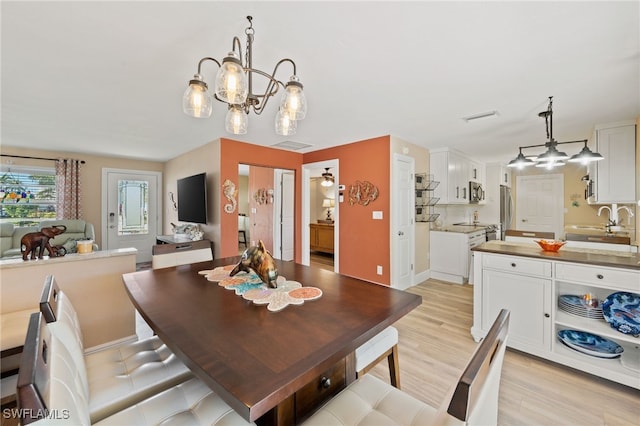 dining room featuring a chandelier, sink, and light hardwood / wood-style floors