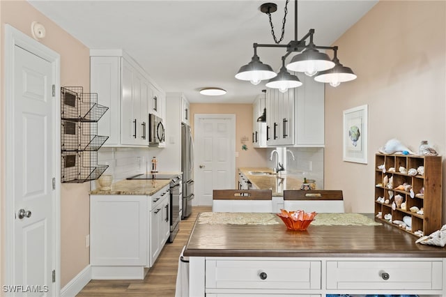 kitchen with white cabinetry, appliances with stainless steel finishes, butcher block counters, and backsplash