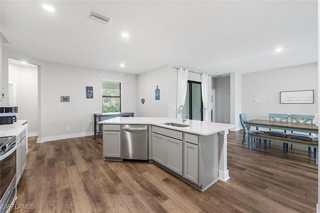 kitchen with gray cabinetry, appliances with stainless steel finishes, sink, dark hardwood / wood-style floors, and a center island with sink