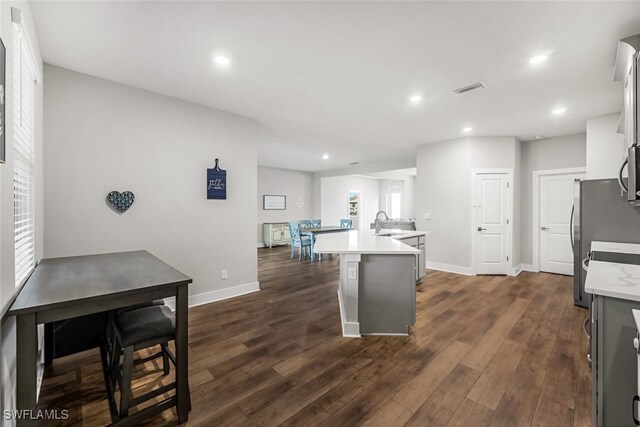 kitchen featuring a center island with sink, stainless steel appliances, a wealth of natural light, and dark hardwood / wood-style flooring