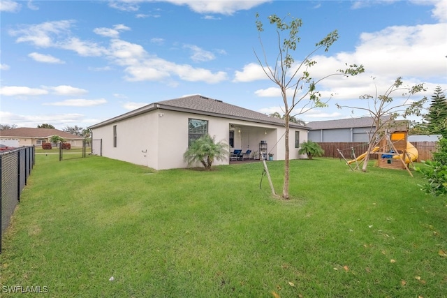 back of house with a yard and a playground