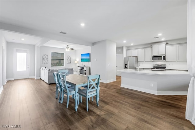 dining space with sink, dark wood-type flooring, and ceiling fan