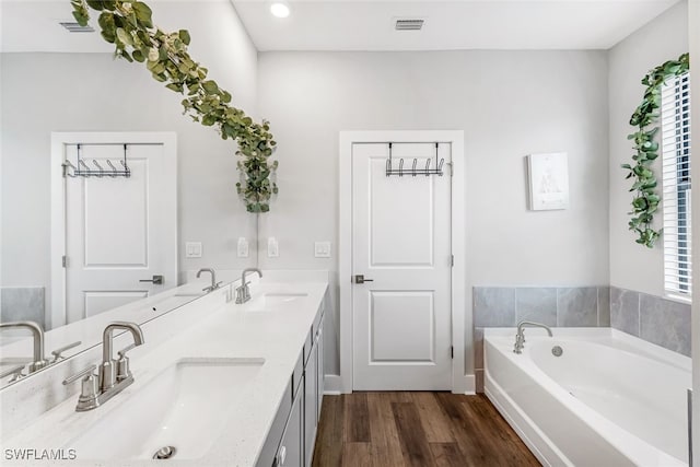 bathroom with vanity, hardwood / wood-style flooring, and a washtub