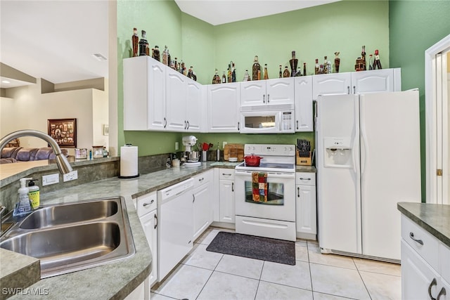 kitchen featuring white appliances, light tile patterned flooring, sink, and white cabinets