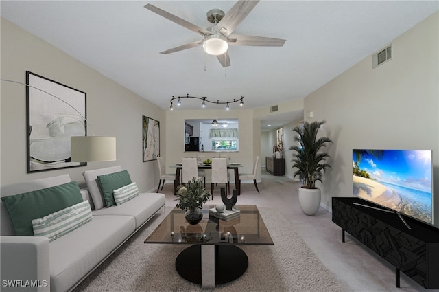 carpeted living room featuring track lighting and ceiling fan