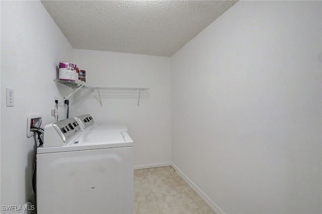 washroom with a textured ceiling and washing machine and dryer