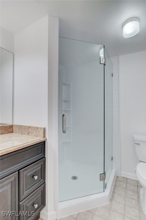 bathroom with toilet, a shower with shower door, vanity, and tile patterned floors