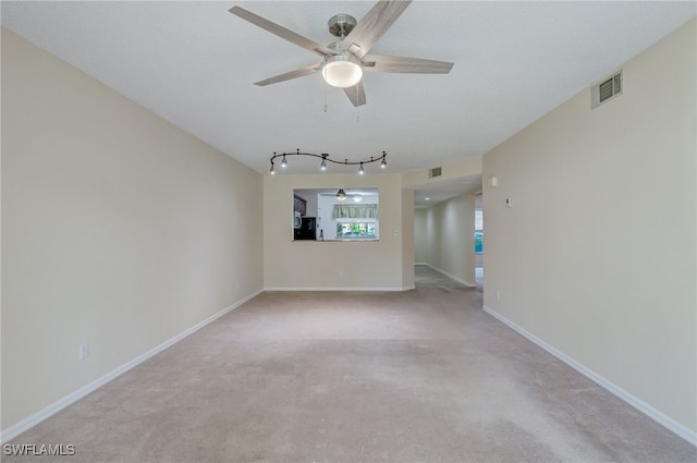 carpeted spare room with ceiling fan and rail lighting