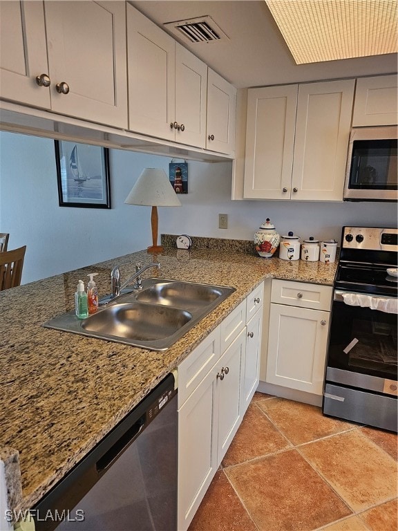 kitchen featuring appliances with stainless steel finishes, sink, white cabinets, light stone counters, and light tile patterned floors