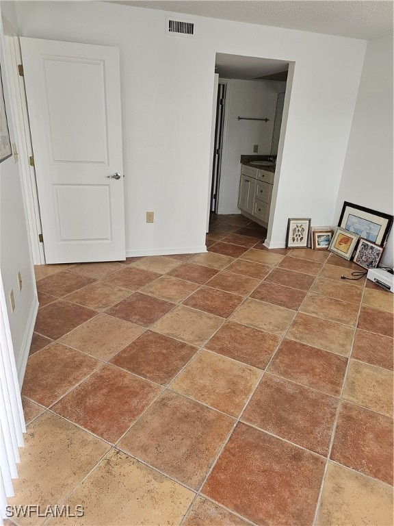 unfurnished bedroom with ensuite bathroom and sink