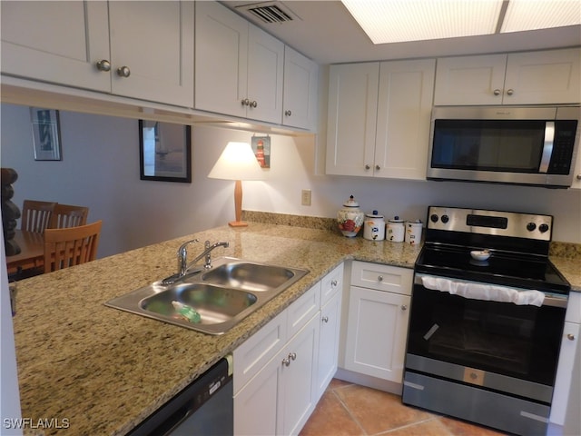 kitchen with light stone counters, light tile patterned floors, white cabinetry, sink, and stainless steel appliances