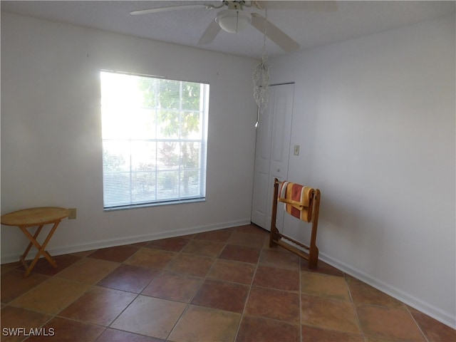 tiled spare room with ceiling fan