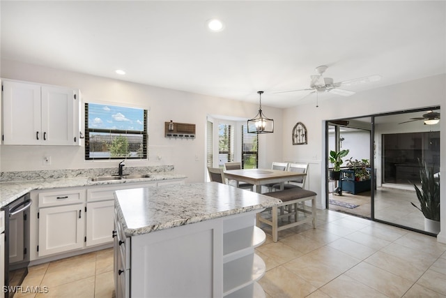 kitchen with white cabinets, sink, ceiling fan with notable chandelier, pendant lighting, and a center island