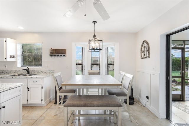 dining area featuring light tile patterned flooring, sink, ceiling fan with notable chandelier, and a wealth of natural light