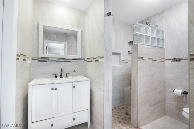 bathroom with vanity, toilet, tile walls, and tiled shower