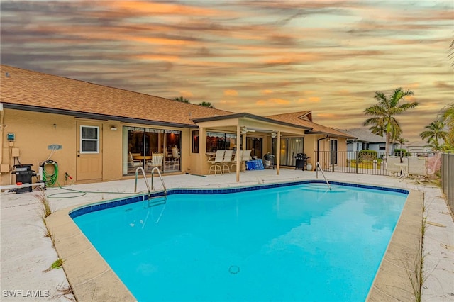 pool at dusk featuring a patio