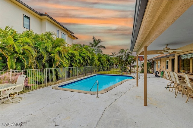 pool at dusk featuring a patio area and ceiling fan