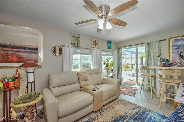 living room featuring a textured ceiling, ceiling fan, and light tile patterned floors