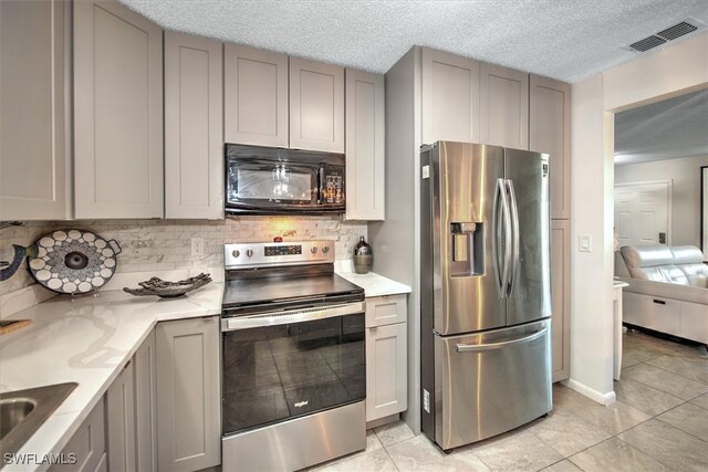 kitchen featuring gray cabinets, tasteful backsplash, and appliances with stainless steel finishes