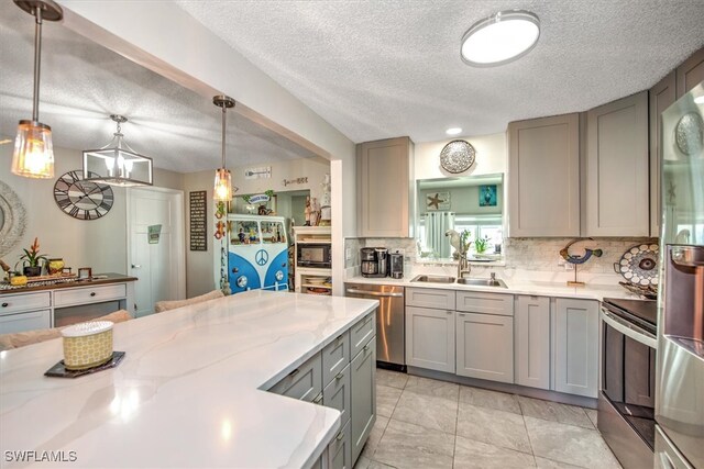 kitchen featuring gray cabinets, stainless steel appliances, hanging light fixtures, and a textured ceiling