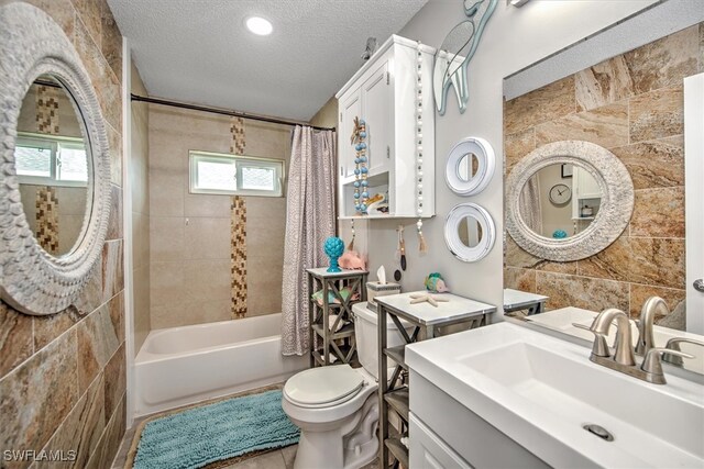 full bathroom featuring shower / bath combo, toilet, tile walls, a textured ceiling, and vanity