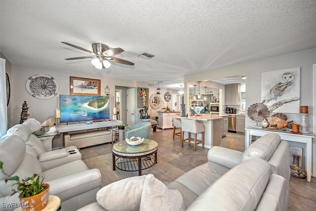 tiled living room with ceiling fan and a textured ceiling