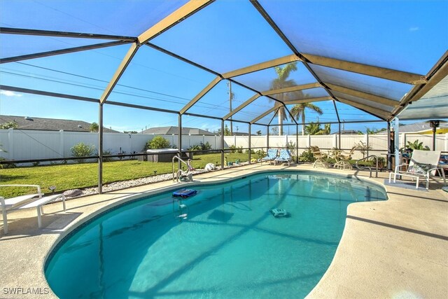 view of pool with a yard, glass enclosure, and a patio area