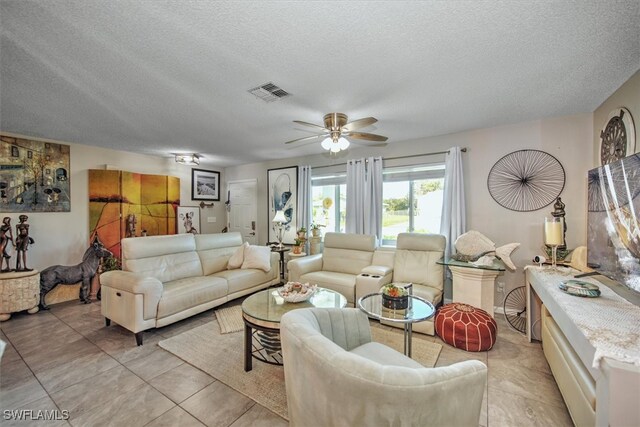 living room featuring light tile patterned flooring, a textured ceiling, and ceiling fan