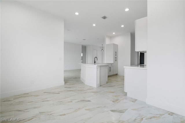 kitchen with sink, an island with sink, and white cabinets