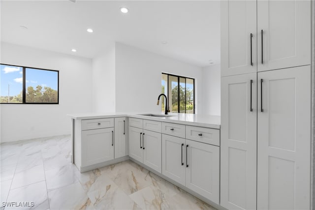 kitchen with sink, kitchen peninsula, and white cabinets