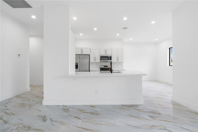 kitchen featuring appliances with stainless steel finishes, kitchen peninsula, and white cabinets