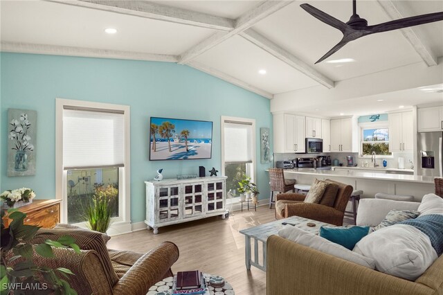 living room with ceiling fan, lofted ceiling with beams, and light wood-type flooring