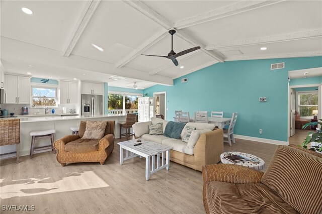 living room with vaulted ceiling with beams, a wealth of natural light, and light wood-type flooring