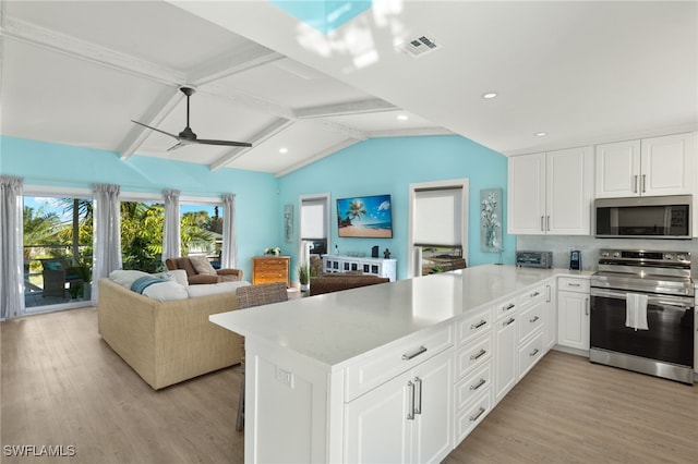 kitchen featuring kitchen peninsula, appliances with stainless steel finishes, ceiling fan, lofted ceiling with beams, and light hardwood / wood-style floors