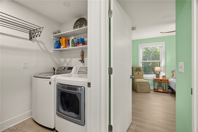 clothes washing area with independent washer and dryer and light hardwood / wood-style floors