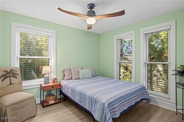 bedroom featuring light wood-type flooring, multiple windows, and ceiling fan