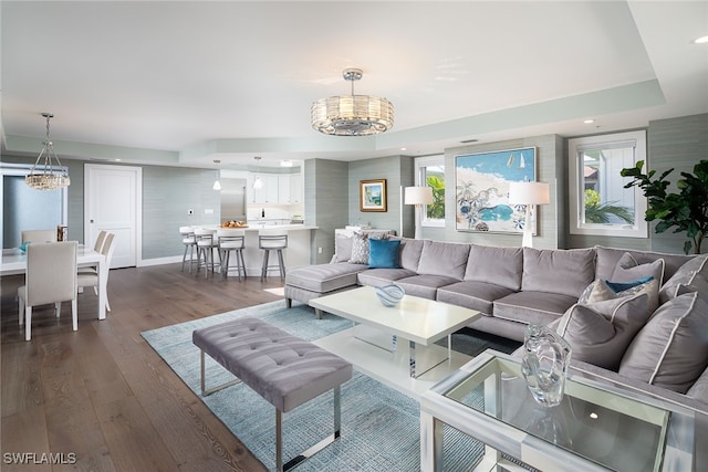 living room with a notable chandelier, dark hardwood / wood-style floors, and a raised ceiling