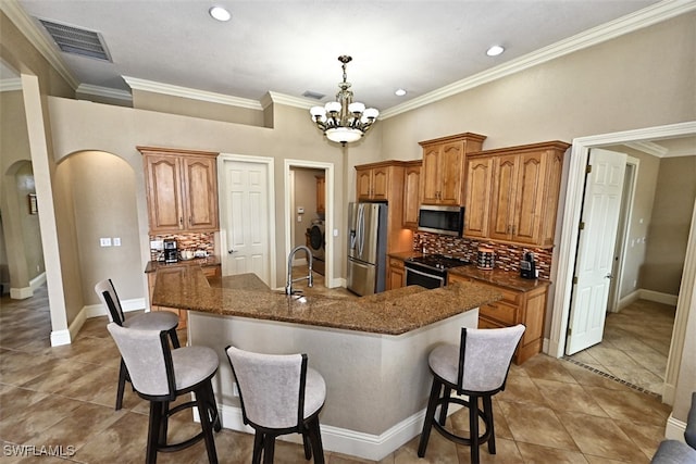 kitchen with a center island with sink, decorative backsplash, stainless steel appliances, and an inviting chandelier