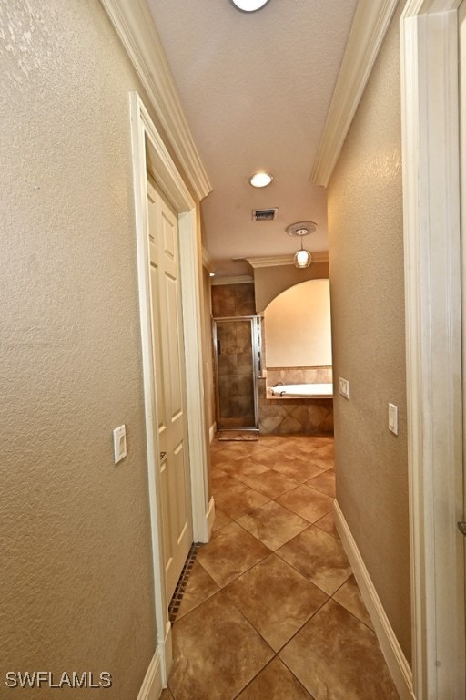 hallway with crown molding, a textured ceiling, and tile patterned flooring