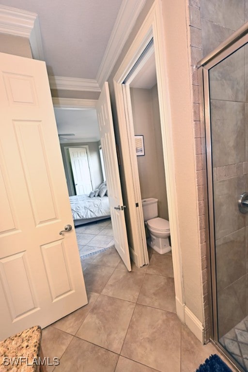 bathroom with tile patterned floors, crown molding, a shower with shower door, and toilet