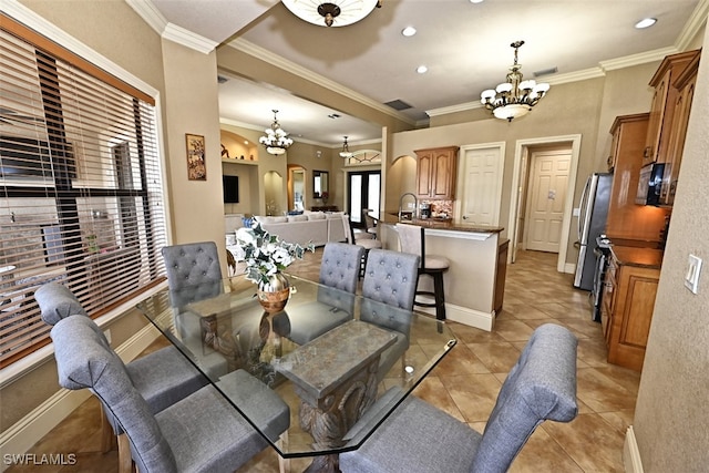 dining space with crown molding, light tile patterned flooring, and an inviting chandelier