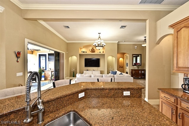 kitchen with ornamental molding, dark stone countertops, a chandelier, and sink