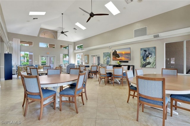 tiled dining area featuring ceiling fan, high vaulted ceiling, and a skylight