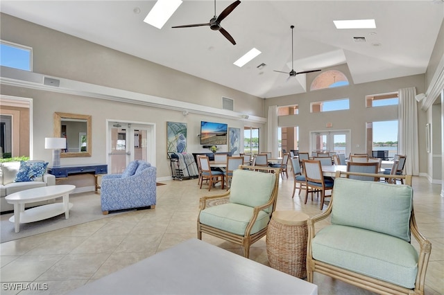 tiled living room with a skylight, high vaulted ceiling, and french doors