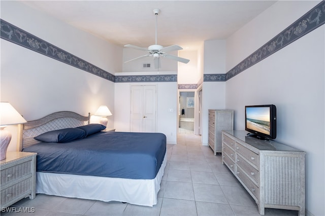 bedroom with ensuite bath, ceiling fan, light tile patterned floors, a towering ceiling, and a closet