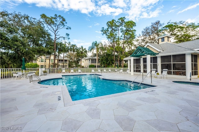 view of swimming pool with a sunroom and a patio